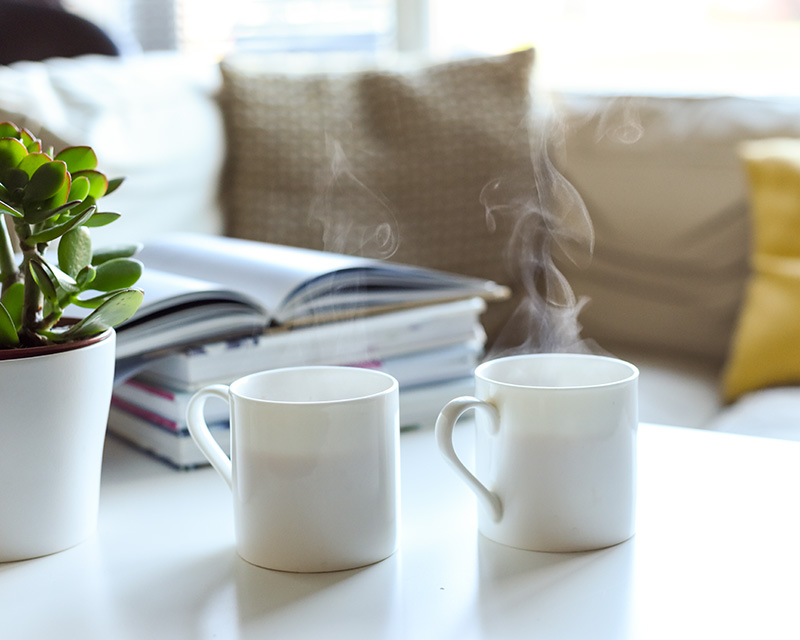 Cups of coffee on a table next to a couch for therapy with Juniper Psychological Associates